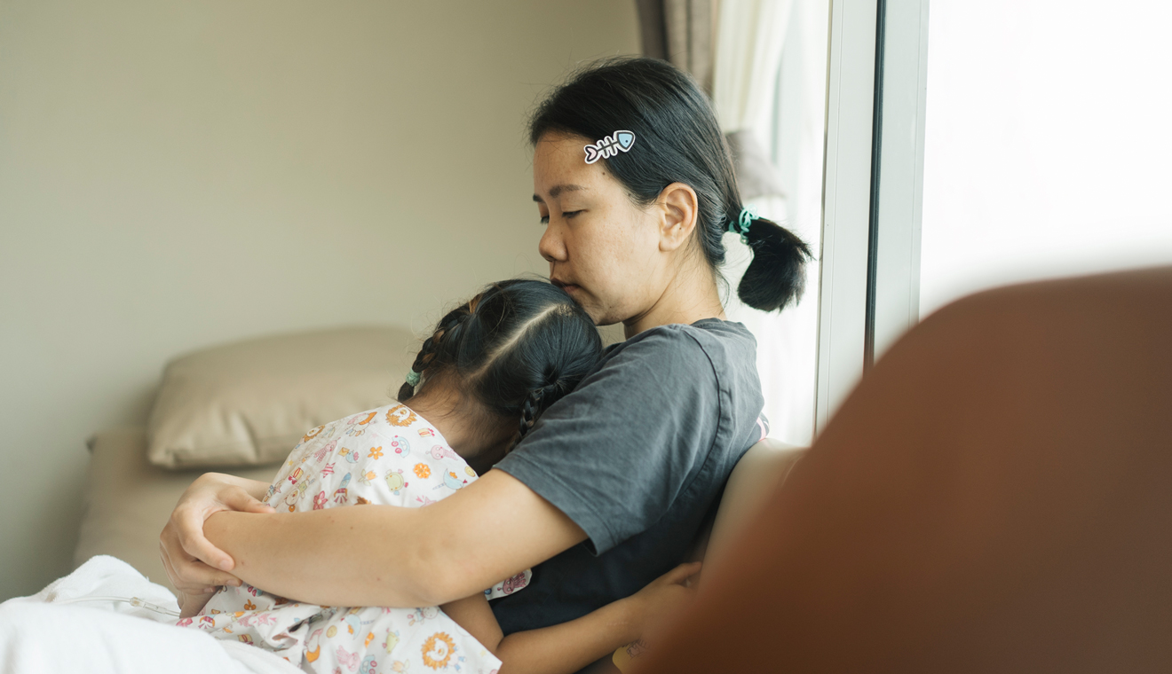 Adult holding and comforting a child while seated indoors