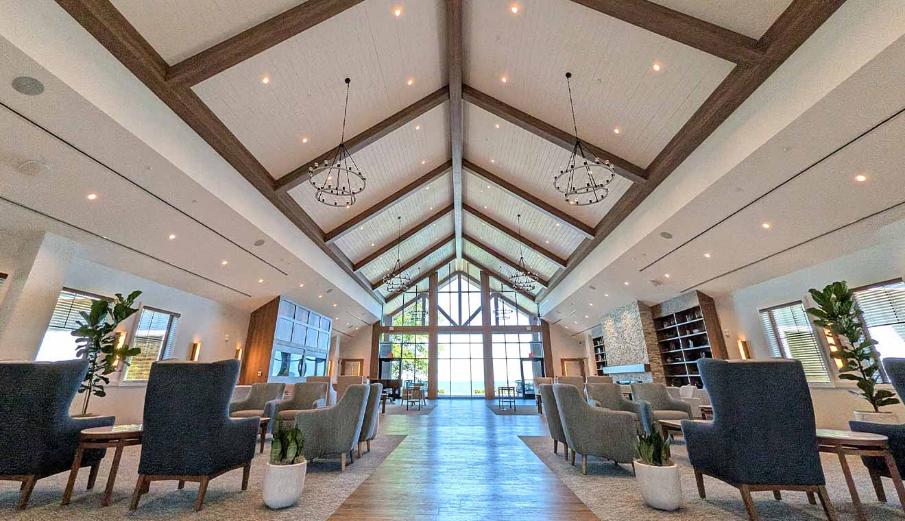 Bright, welcoming community lounge with vaulted ceilings, comfortable seating, and expansive waterfront views