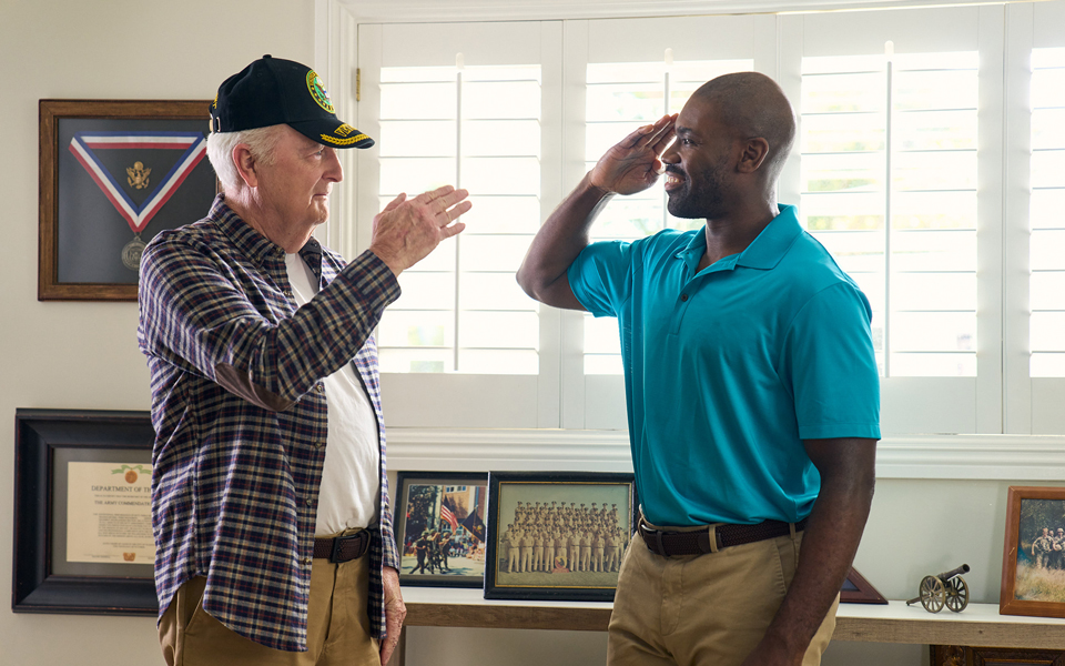 An older man and a younger man saluting together