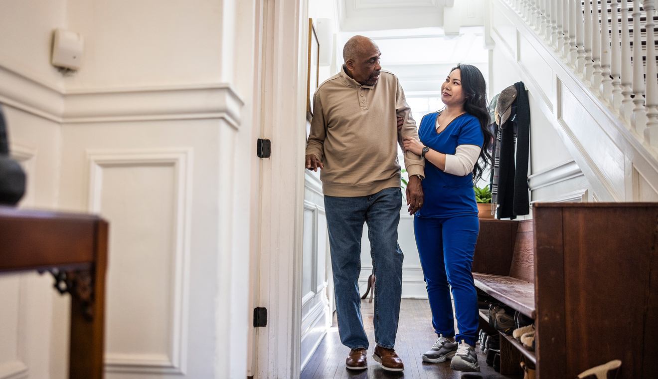 Caregiver helping a person walk safely through the home.