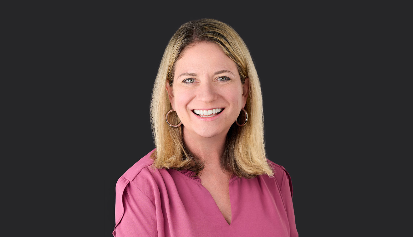 Smiling blonde woman in a pink blouse photographed in a professional studio portrait