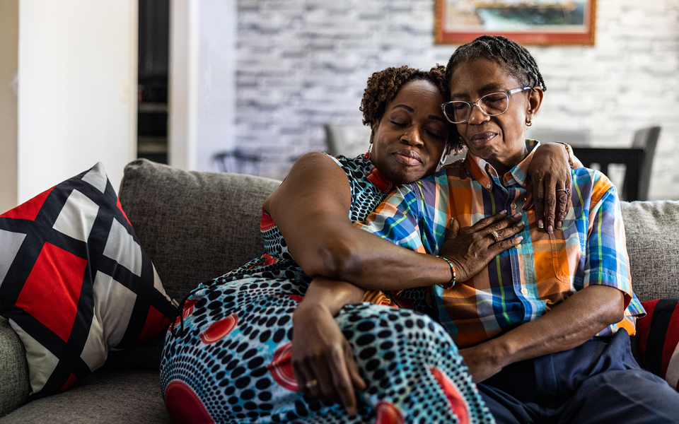 Two people sitting together on a couch sharing a comforting moment.