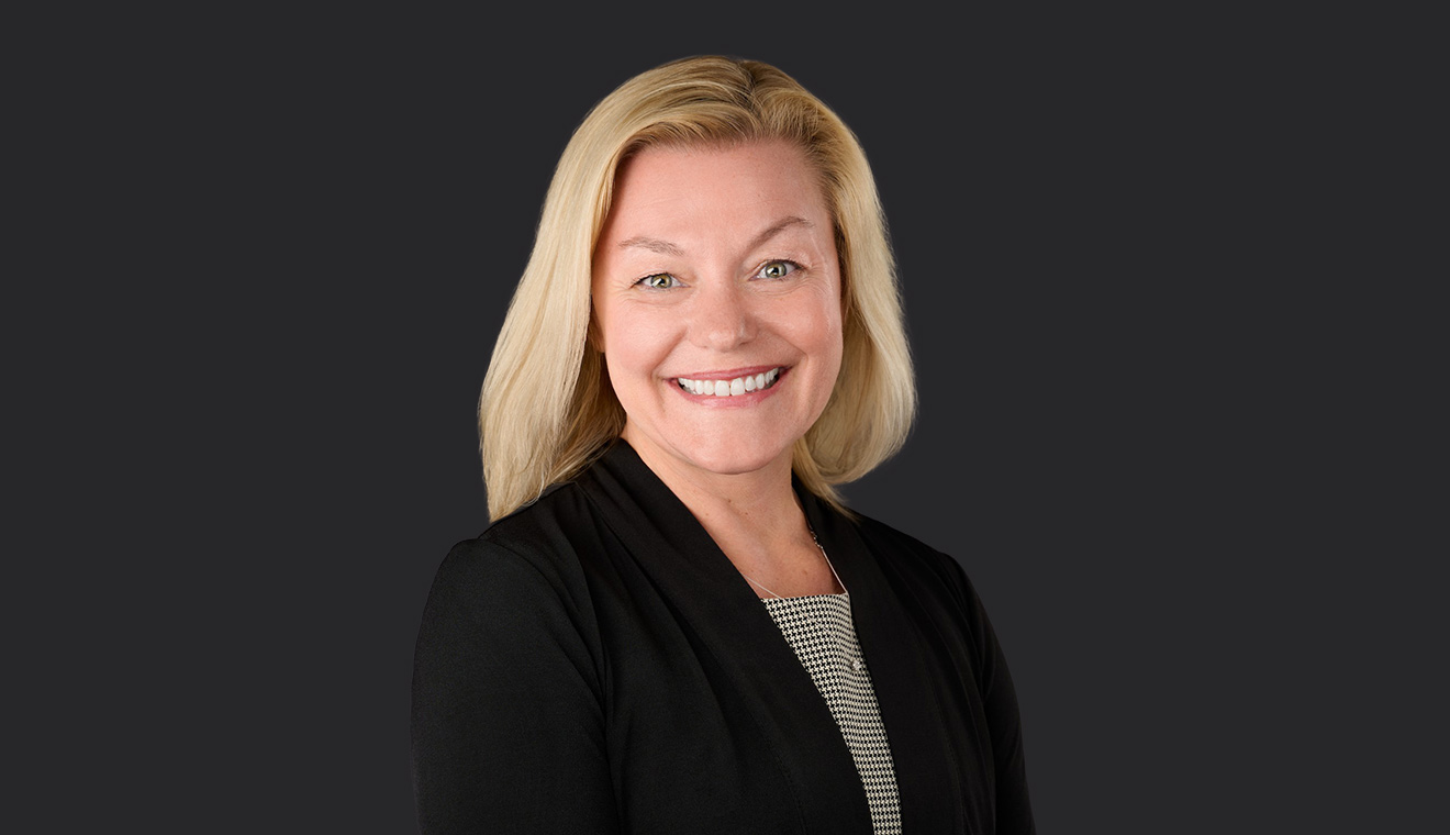 Blonde businesswoman in a black blazer smiling in a professional headshot